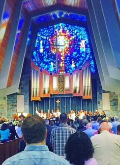 A group of people sitting in a room with a stained glass window

Description automatically generated with low confidence